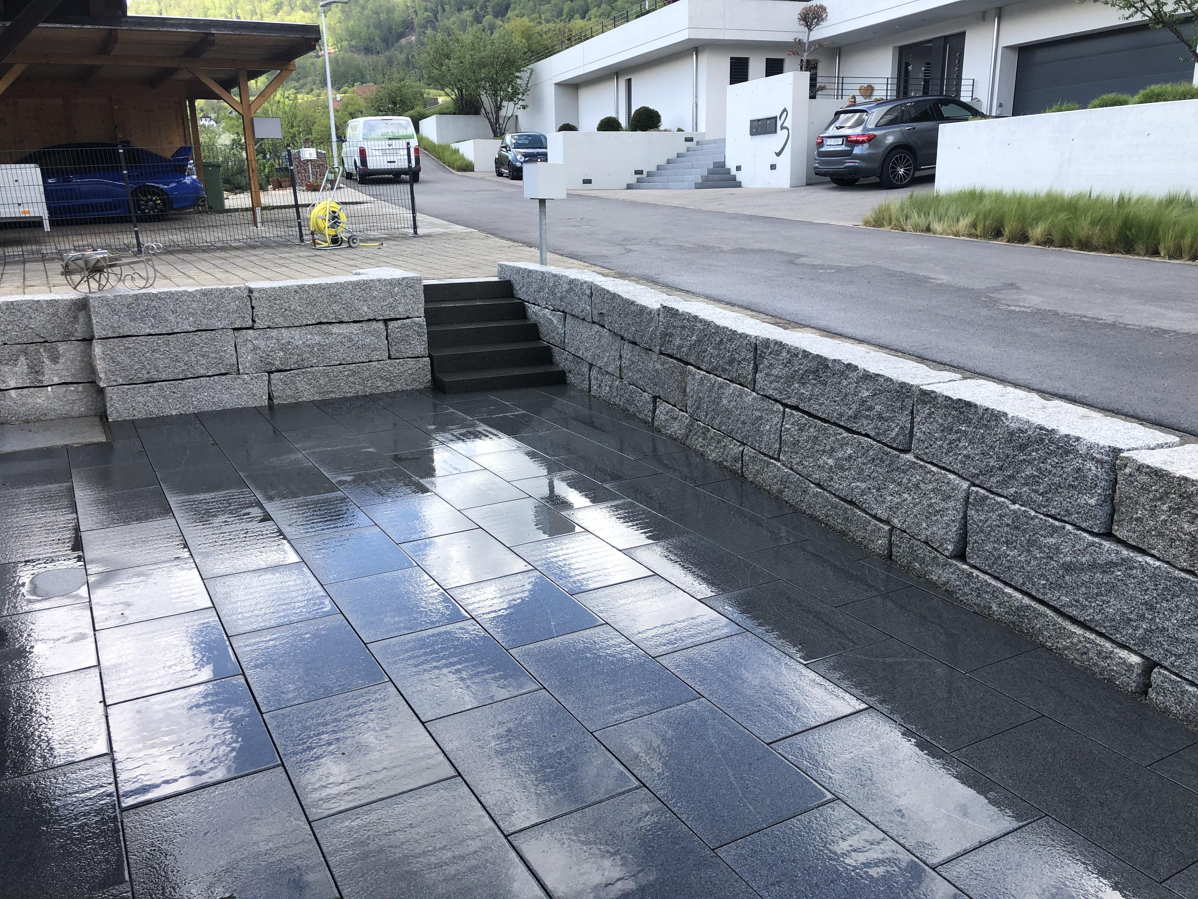 Granitterrasse mit dunklen Platten und Treppenstufen im Regen