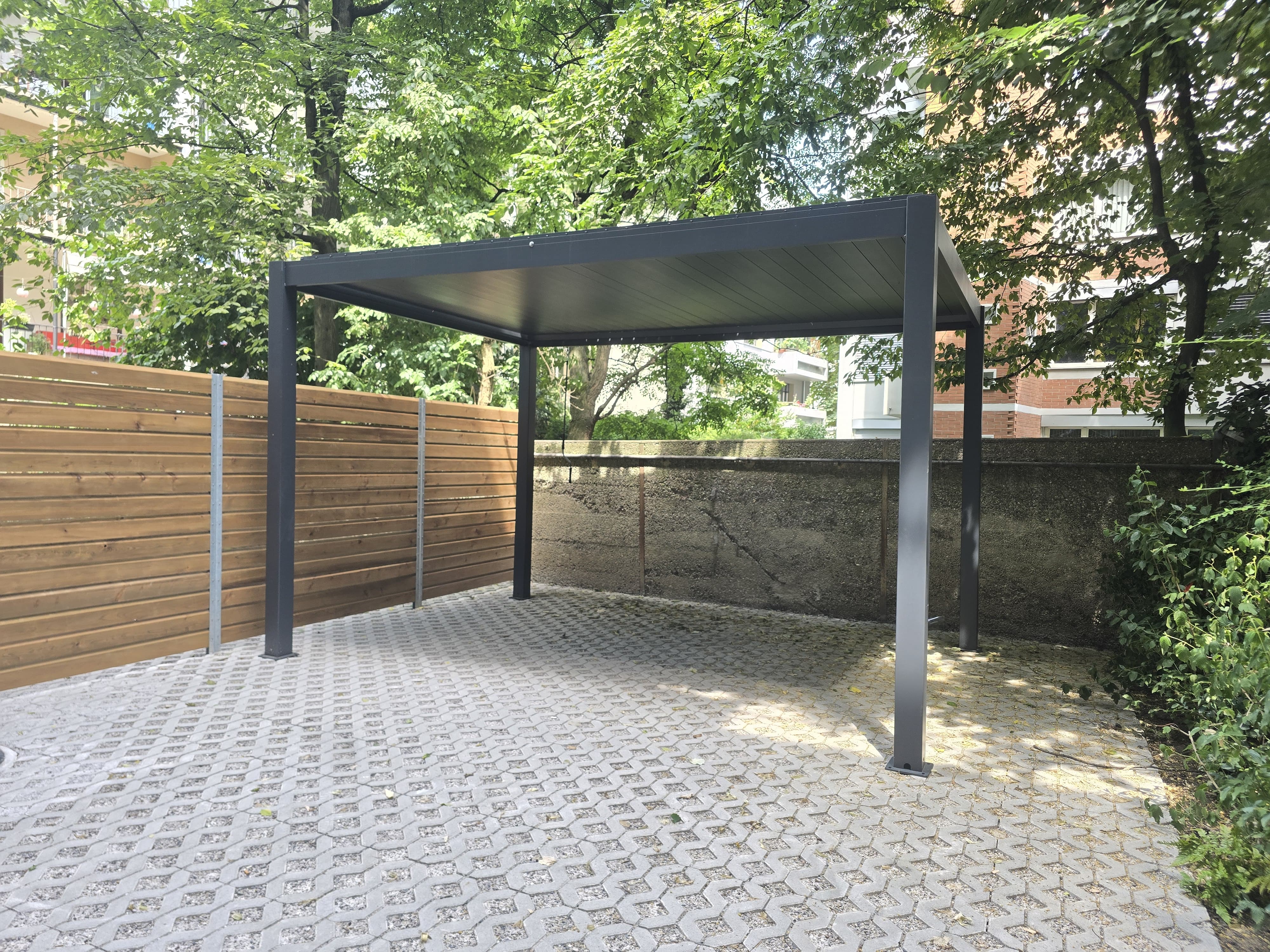 Modernes Metall-Pergola auf Pflastersteinboden mit Holzsichtschutz