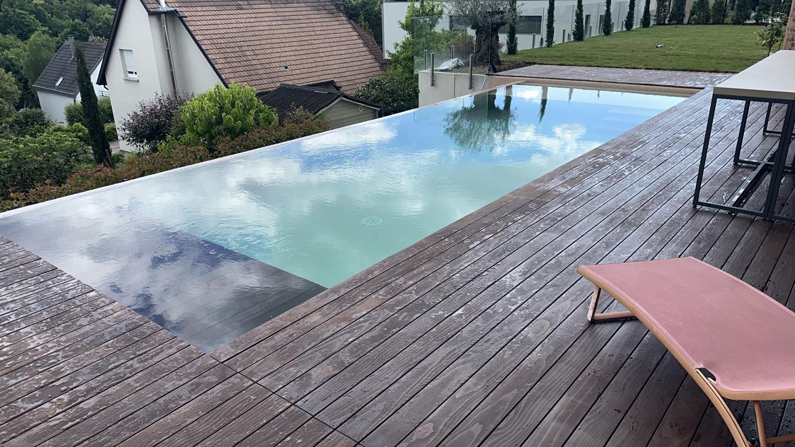 Infinity-Pool mit Holzdeck und Liegebereich