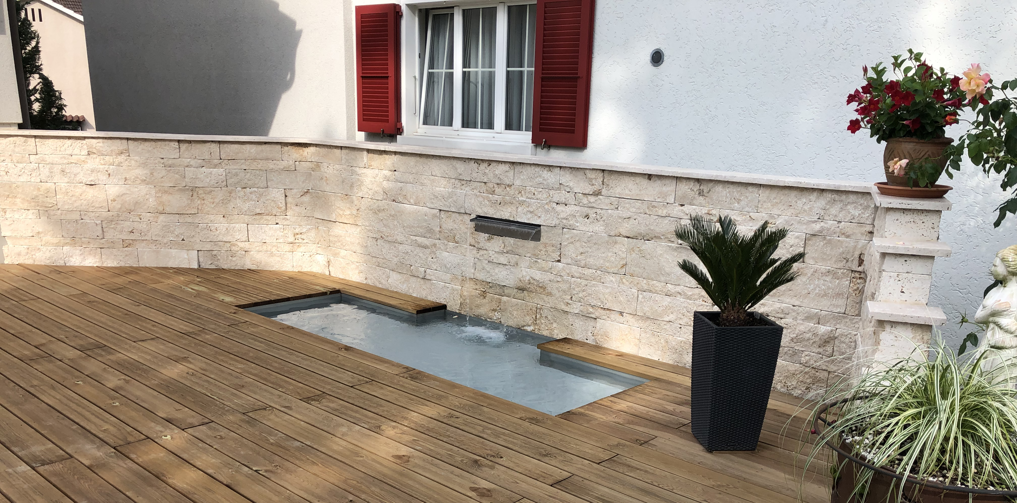 Holzdeck mit Wandwasserfall und Natursteinmauer