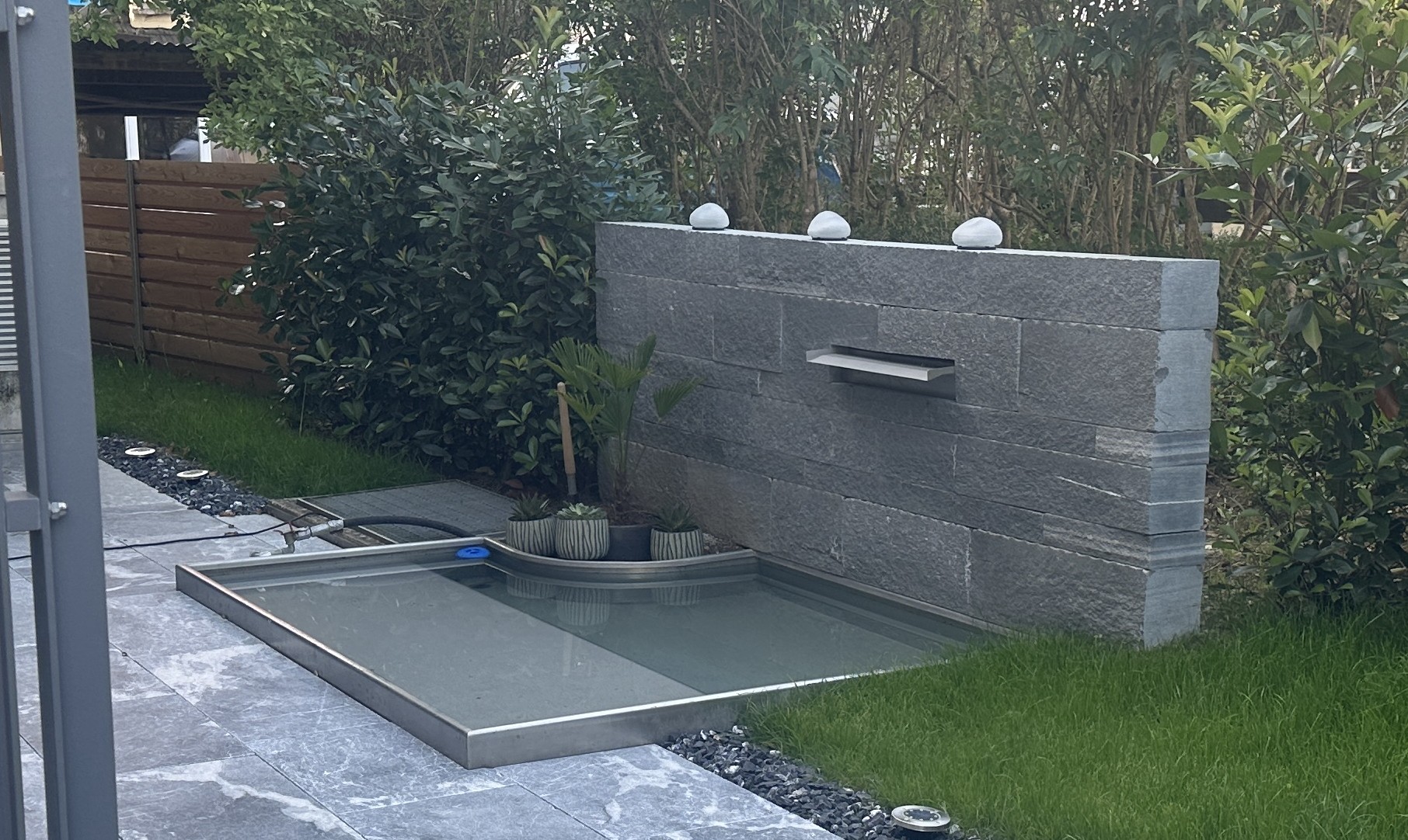Wandbrunnen in Granitmauer mit Edelstahlbecken und Steinkugeln