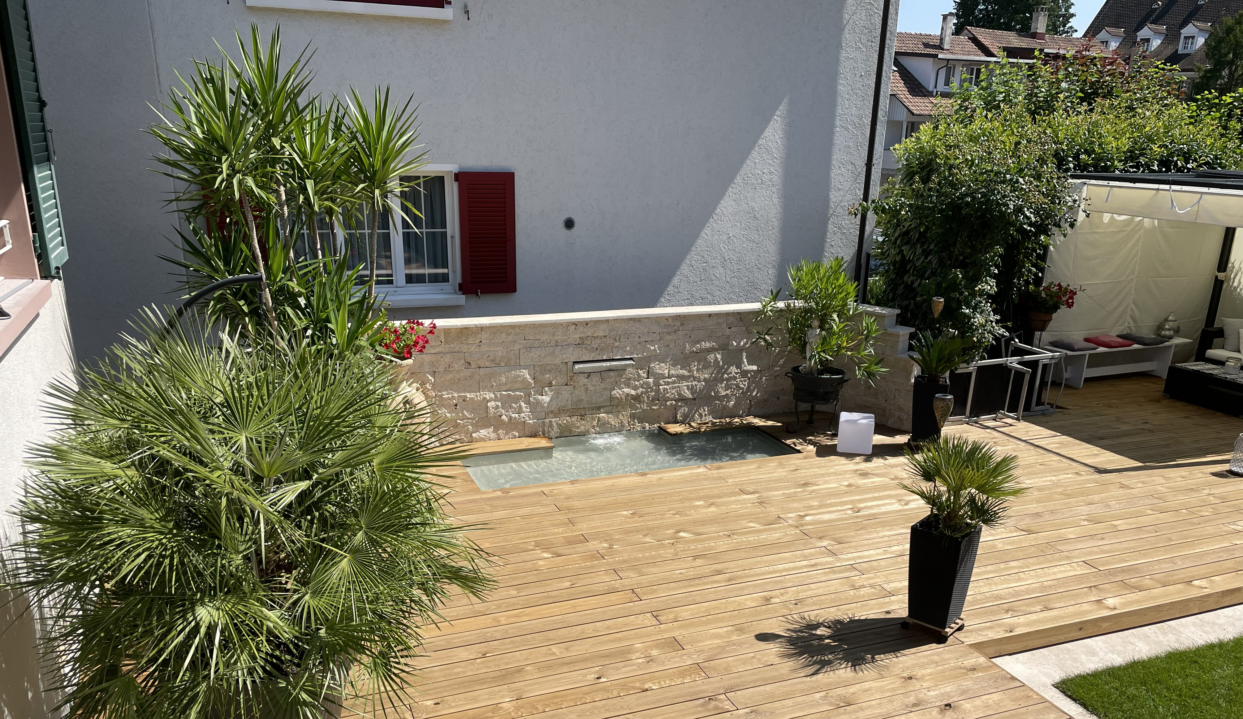 Holzdeck mit eingebautem Wandwasserfall und Bepflanzung