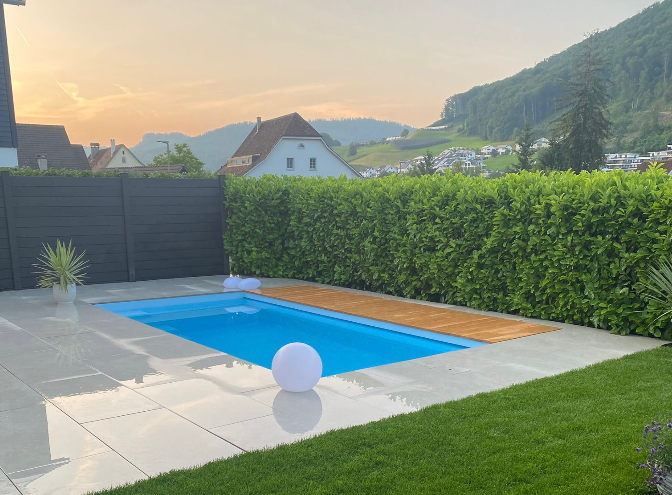 Pool mit Holzverdeck, Granitplatten und Thujahecke